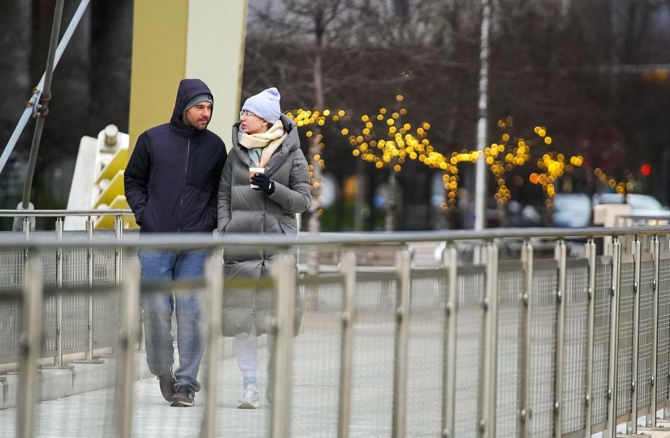 Kornel Rady and Rebecca Knott take a morning walk as a cold front sweeps across downtown Austin on Monday. A sudden drop in temperature and a brisk wind foreshadow the challenges they will face throughout the day.