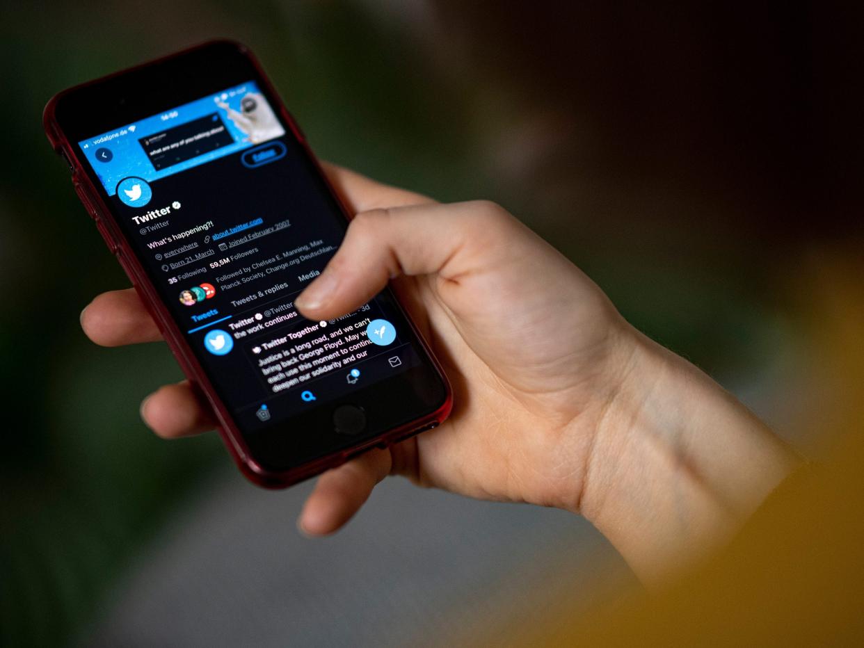A person holds a smartphone with the Twitter app open