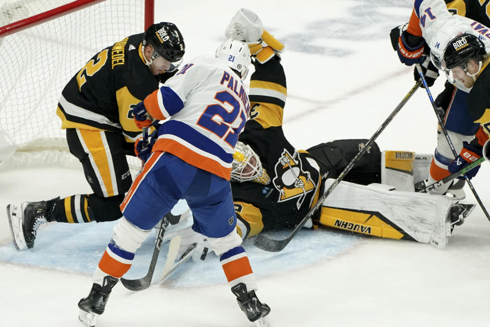 Pittsburgh Penguins goaltender Alex Nedeljkovic (39), center right, makes a save against New York Islanders' Kyle Palmieri (21) during the first period of an NHL hockey game Sunday, Dec. 31, 2023, in Pittsburgh. (AP Photo/Matt Freed)
