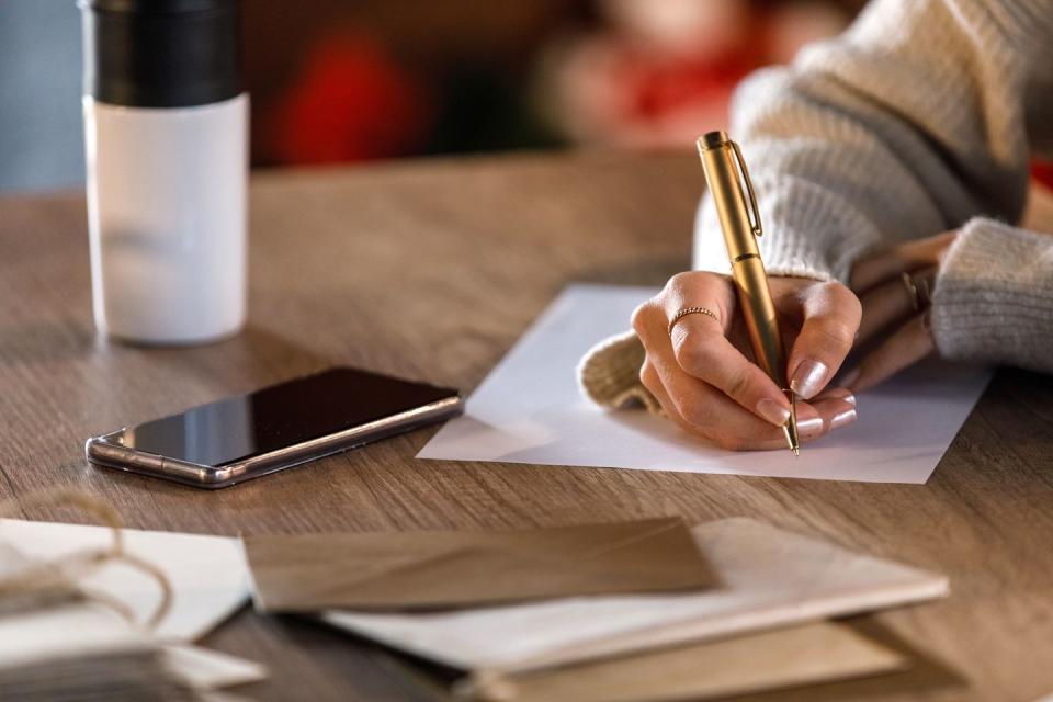 woman writing in card with gold pen