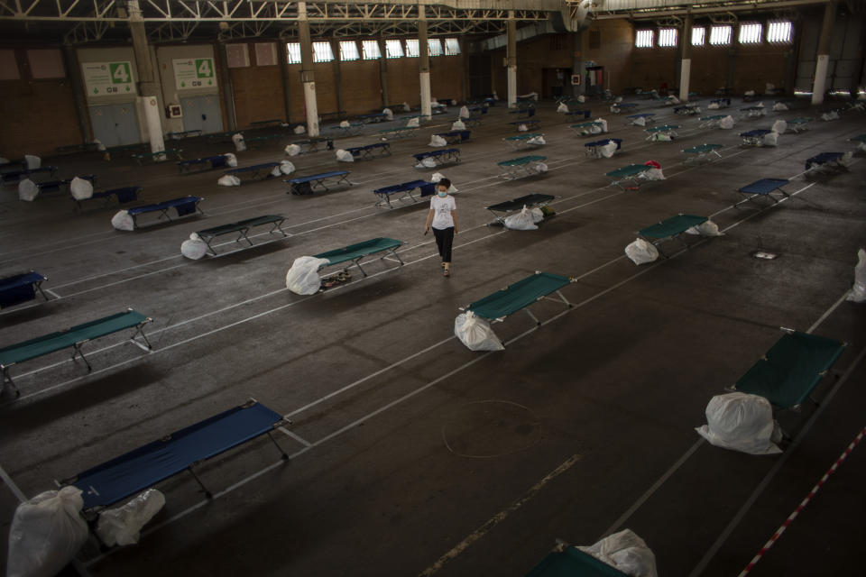 A local worker walks along an exhibition center turned into a temporary seasonal workers' shelter in Lleida, Spain, Thursday, July 2, 2020. Authorities in northeast Spain have ordered the lockdown of a county around the city of Lleida due to worrying outbreaks of the COVID-19 virus. Catalan regional authorities announced Saturday, July 4, 2020 that as of noon local time movement will be restricted to and from the county of El Segriá around Lleida which is home to over 200,000 people. Residents will have until 4 p.m. to enter the area. The new outbreaks are linked to agricultural workers in the rural area. (AP Photo/Emilio Morenatti)