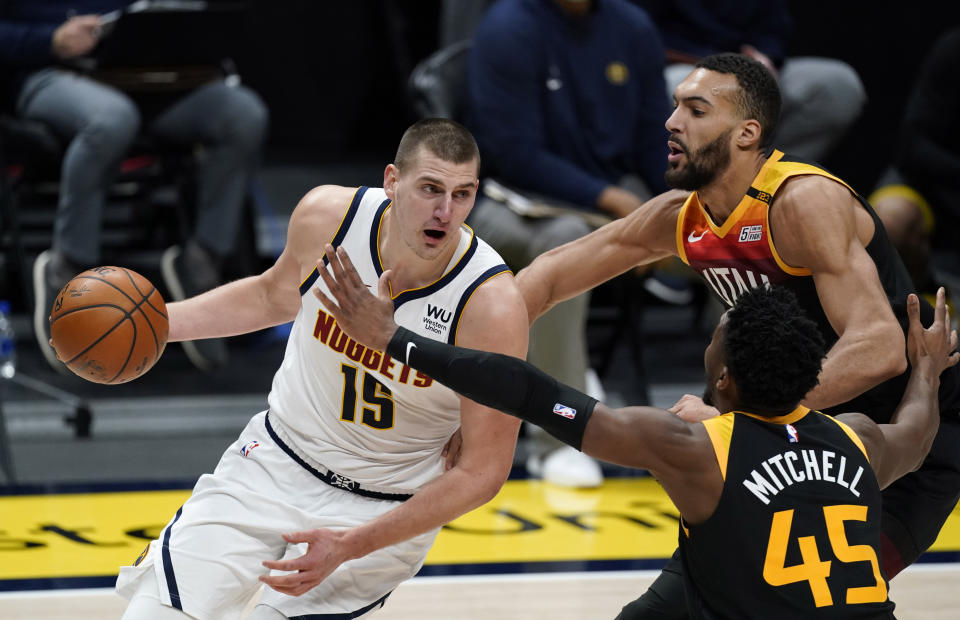 Denver Nuggets center Nikola Jokic, left, drives to the basket as Utah Jazz guard Donovan Mitchell, front right, and center Rudy Gobert defend in the second half of an NBA basketball game Sunday, Jan. 31, 2021, in Denver. (AP Photo/David Zalubowski)