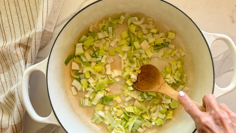 hand stirring leeks in pot