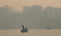 Men fish in the in the Cuiaba River in a dense smoke caused by fires, at the Encontro das Aguas state park in the Pantanal wetlands near Pocone, Mato Grosso state, Brazil, Sunday, Sept. 13, 2020. This year the Pantanal is exceptionally dry and burning at a record rate. The fires have been so intense that its smoke on Sept. 18 reached Sao Paulo, 900 miles away. (AP Photo/Andre Penner)