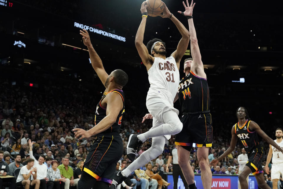 Cleveland Cavaliers center Jarrett Allen (31) drives to the basket between Phoenix Suns' Eric Gordon, left, and Drew Eubanks, right, during the second half of an NBA basketball game in Phoenix, Wednesday, April. 3, 2024. (AP Photo/Darryl Webb)