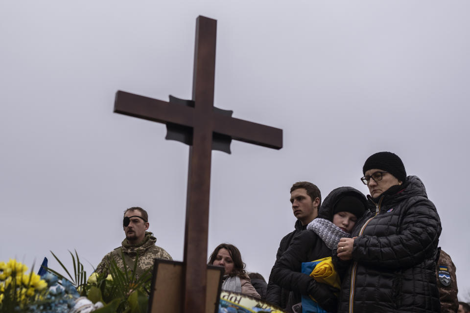 Sophia, second right, hugs her grandmother Anna as she stands with other family members near the grave of her father, soldier Yurii Hubiak, during a funeral at Lviv cemetery, western Ukraine, Friday, Feb. 24, 2023. Hubiak died near Bakhmut a week ago.(AP Photo/Petros Giannakouris)