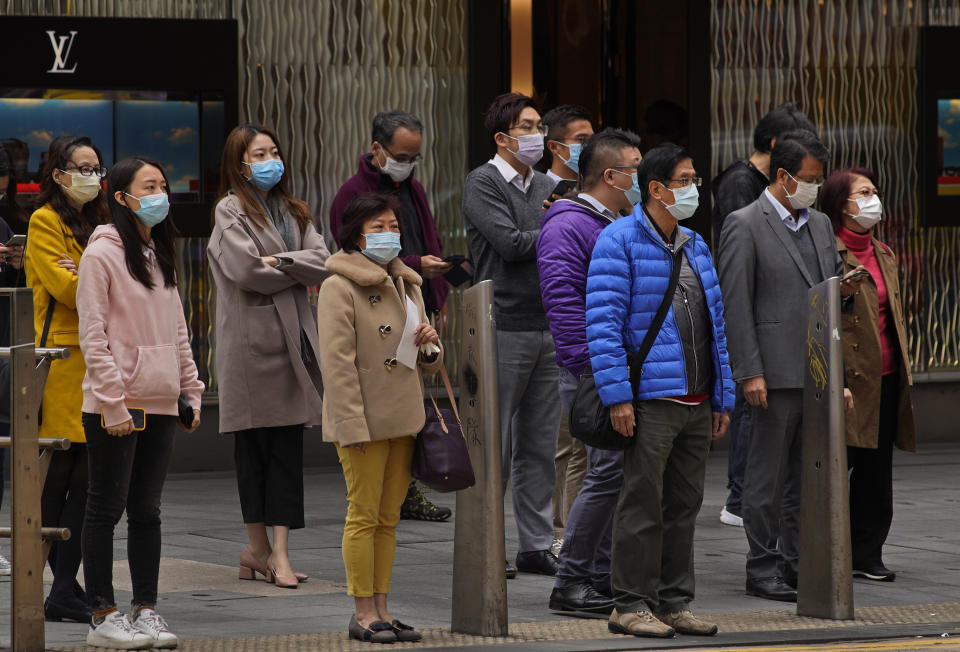 People wear masks on a downtown street corner in Hong Kong, Tuesday, Feb. 4, 2020. Hong Kong on Tuesday reported its first death from a new virus, a man who had traveled from the mainland city of Wuhan that has been the epicenter of the outbreak. (AP Photo/Vincent Yu)