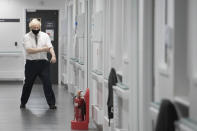 Britain's Prime Minister Boris Johnson rolls up his sleeves, during a visit to Chase Farm Hospital in north London, Monday Jan. 4, 2021. Johnson warned Sunday that more onerous lockdown restrictions in England are likely in the coming weeks as the country reels from a coronavirus variant that has pushed infection rates to their highest recorded levels. (Stefan Rousseau/Pool Photo via AP)
