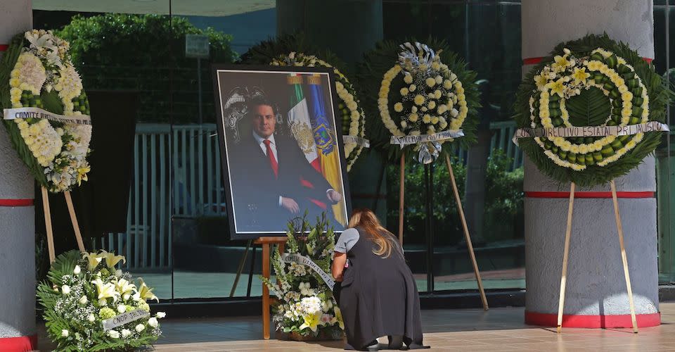 Una mujer coloca un par de veladoras al pie del altar que fue instalado en las instalaciones del Comité Directivo Estatal del PRI por el asesinato del ex Gobernador de Jalisco Jorge Aristóteles Sandoval Díaz.