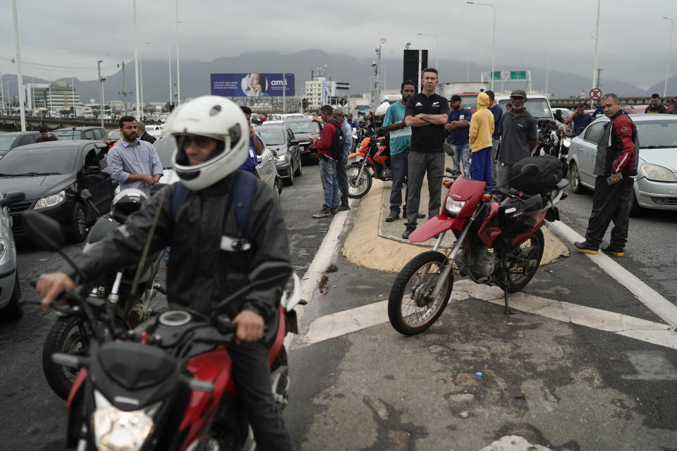 People wait at a blocked access of the bridge connecting the city of Niteroi to Rio de Janeiro , Brazil, Tuesday, Aug. 20, 2019 during a hostage standoff. An armed man holding dozens of people hostage on a public bus and threatening to set the vehicle on fire was seized by police after a four-hour long standoff, Brazilian police said.  (AP Photo/Leo Correa)