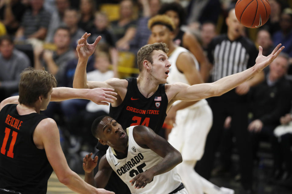 Oregon State forward Kylor Kelley, back, reaches out for a rebound over Colorado guard McKinley Wright IV, as Oregon State guard Zach Reichle looks on in the second half of an NCAA college basketball game Sunday, Jan. 5, 2020, in Boulder, Colo. Oregon State came from behind to win 76-68. (AP Photo/David Zalubowski)