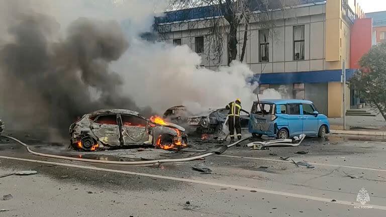 En esta fotografía tomada de un video difundido por el canal de Telegram del Ministerio de Situaciones de Emergencia de Rusia el sábado 30 de diciembre de 2023, se ve a bomberos que extinguen vehículos en llamas después de un ataque en Belgorod, Rusia. (Canal de Telegram del Ministerio de Situaciones de Emergencia de Rusia via AP)