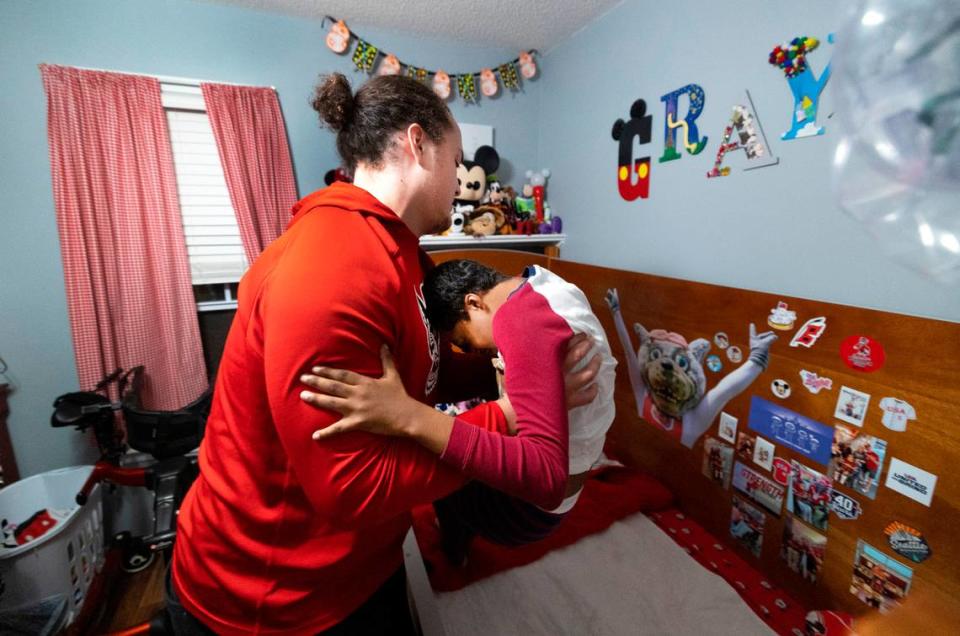 N.C. State offensive lineman Dylan McMahon lifts Grayson Ketchie from his bed at Grayson’s home in Garner Wednesday evening, Oct. 18, 2023. Ketchie, 12, has been suffering from severe neurological issues since he was a baby. He has been a Wolfpack fan since he was three and the players made a surprise visit to his home that evening.