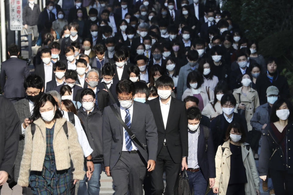 Commuters wearing face masks to protect against the spread of the coronavirus walk on a street in Tokyo, Tuesday, Nov. 17, 2020. Japan has set a record for its daily new cases exceeding 2,100 cases of the coronavirus, the health ministry said Thursday, Nov. 19, 2020 as Japanese Prime Minister Yoshihide Suga called for maximum caution but without asking for restrictions on traveling or business activities. (AP Photo/Koji Sasahara)