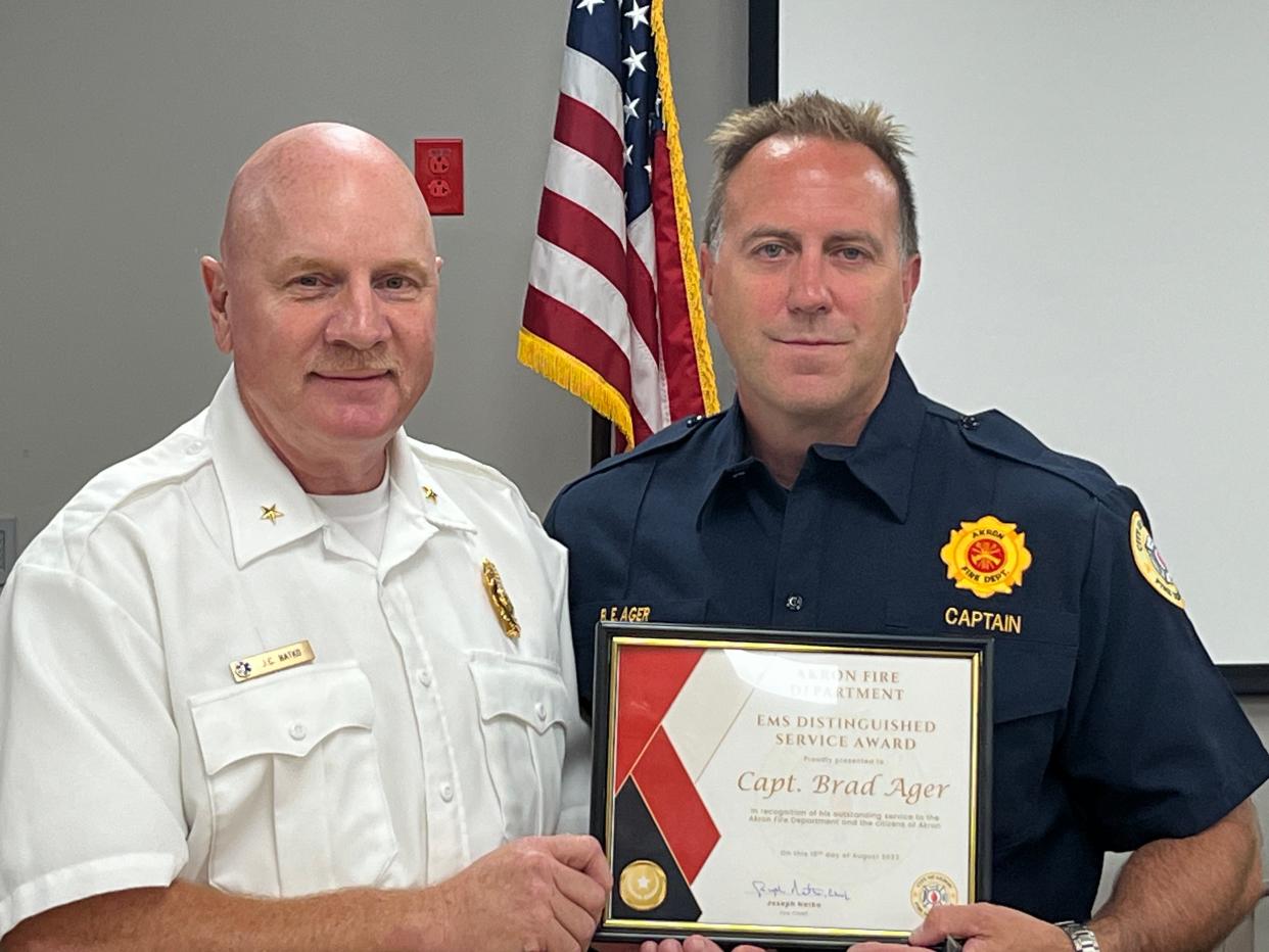 Akron Fire Department Chief Joseph Natko presents Capt. Brad Ager with the EMS Distinguished Service award for his conduct last month.