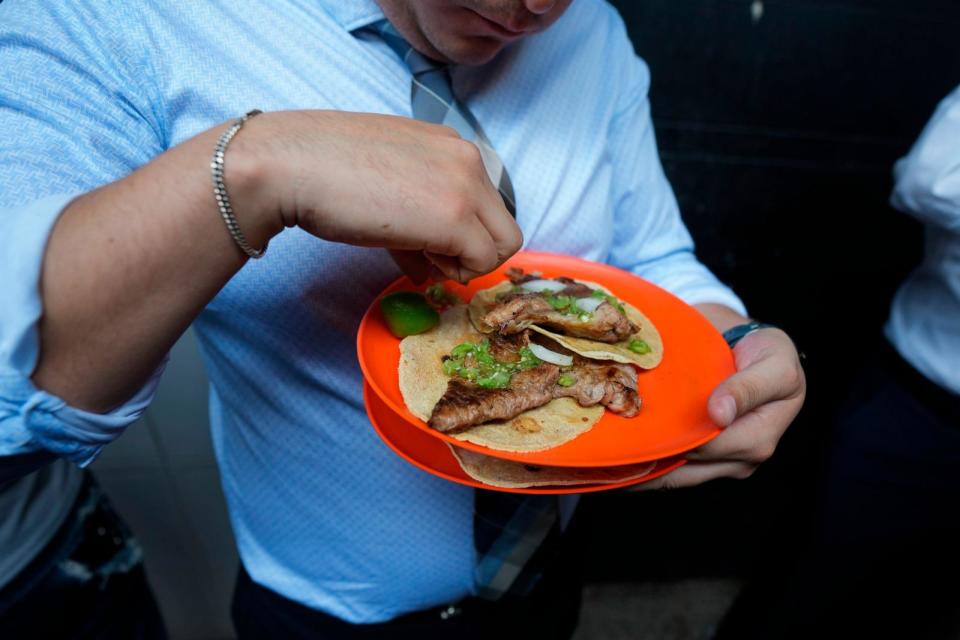 PHOTO: A customer finishes squeezing lime juice on his tacos at the Tacos El Califa de León stand, in Mexico City, May 15, 2024.   (Fernando Llano/AP)