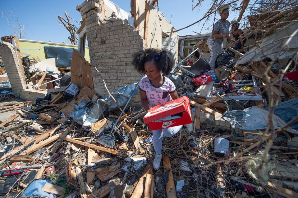 Alaina Dean, 8, her mother Shannekia Miles, background, and other family members salvage what they can from their home on 7th Street in Rolling Fork on Saturday after a tornado cut through the small Delta town Friday night.