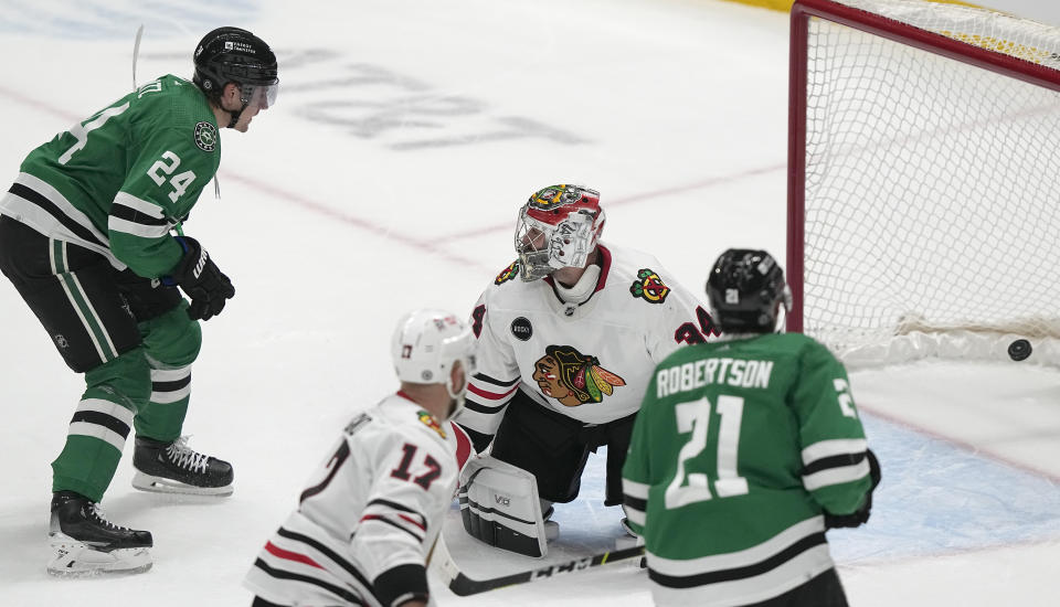 Chicago Blackhawks goaltender Petr Mrazek (34) allows a goal by Dallas Stars center Roope Hintz (24) with Stars' Jason Robertson (21) and Blackhawks' Nick Foligno (17) looking on during overtime play in an NHL hockey game in Dallas, Friday, Dec. 29, 2023. (AP Photo/LM Otero)