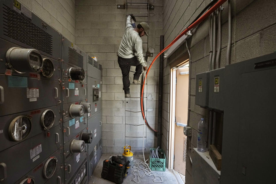 FILE - Michael Villa, a service tech at Total Refrigeration, works on a commercial air conditioning roof unit July 19, 2023, in Laveen, Ariz. (AP Photo/Ross D. Franklin, File)