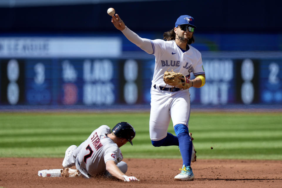 Toronto Blue Jays designated hitter Bo Bichette (11) get the force out on Cleveland Guardians center fielder Myles Straw (7) while trying to turn a double play during the third inning of a baseball game in Toronto, Sunday, Aug. 27, 2023. (Frank Gunn/The Canadian Press via AP)