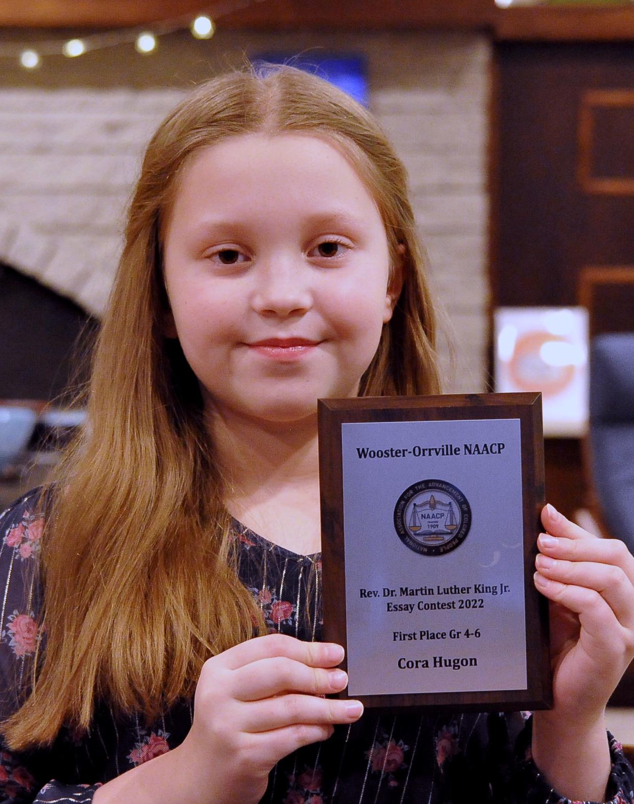 Cora Hugon holds the plaque she received for winning the MLK Essay Contest in her division.