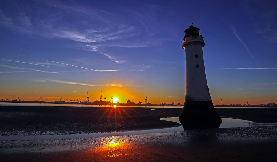 <em>The sun rises behind the lighthouse at New Brighton beach on the Wirral, Merseyside (PA)</em>