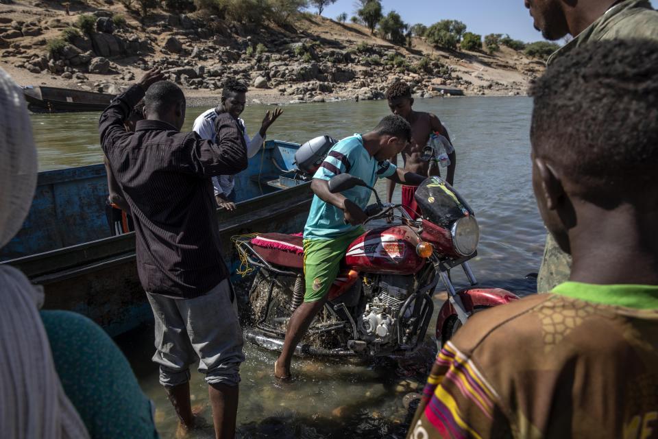 Tigray refugees who fled the conflict in the Ethiopia's Tigray arrive with their motorcycle on the banks of the Tekeze River on the Sudan-Ethiopia border, in Hamdayet, eastern Sudan, Tuesday, Dec. 1, 2020. (AP Photo/Nariman El-Mofty)