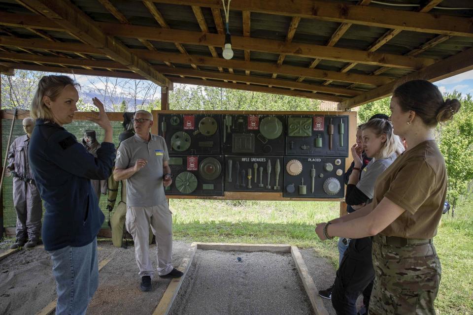 Demining instructor Artur Tigani, second left, briefs a group of Ukrainian female emergency services personnel for specialist training in explosive ordnance disposal and survey training in the western Kosovo city of Peja on Monday, April 25, 2022. Six Ukrainian women have started to be trained in Kosovo to dispose of explosive ordnance that have contaminated their country invaded by Russia. (AP Photo/Visar Kryeziu)