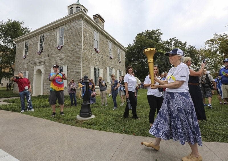 Former Indiana first lady Judy O'Bannon carries the first leg of the Indiana bicentennial relay with the former Indiana State Capitol behind her on the town square in Corydon, Ind.  AP Photo/The Courier-Journal, MICHAEL CLEVENGER