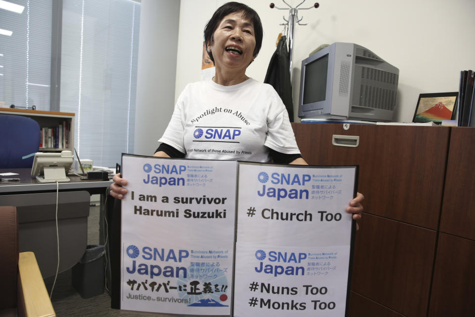 FILE - In this Nov. 25, 2019, file photo, Survivors Network of Those Abused by Priests (SNAP) Japan local leader Harumi Suzuki holds signs while speaking during an interview with The Associated Press in Tokyo. Suzuki has filed a suit against the Roman Catholic Church in Japan alleging that a priest raped her four decades ago, as the church's unfolding worldwide sexual abuse crisis gradually reaches Japan. (AP Photo/Koji Sasahara, File)