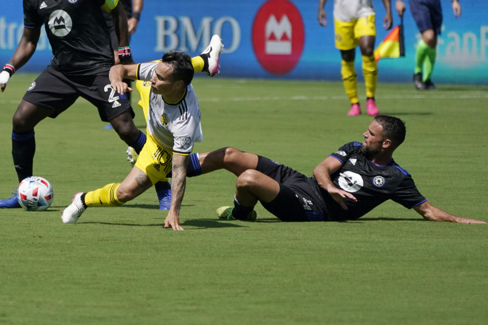 Columbus Crew midfielder Lucas Zelarayan, left, falls to the field as he goes for the ball against CF Montréal defender Rudy Camacho during the first half of an MLS soccer match, Saturday, May 1, 2021, in Fort Lauderdale, Fla. (AP Photo/Lynne Sladky)