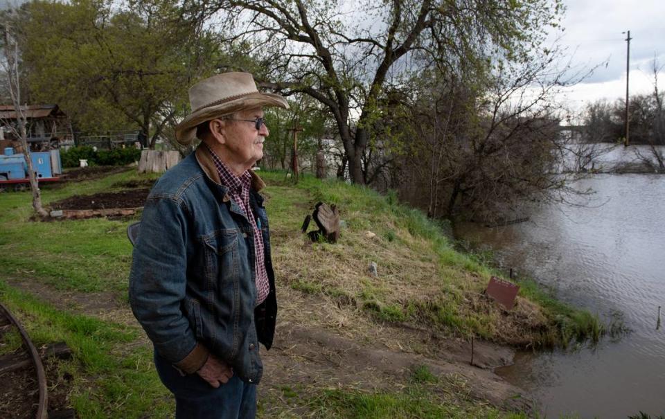 Raymond Washburn looks out at the rising San Joaquin River from his home on Ash Avenue in Patterson, Calif., Wednesday, March 22, 2023.