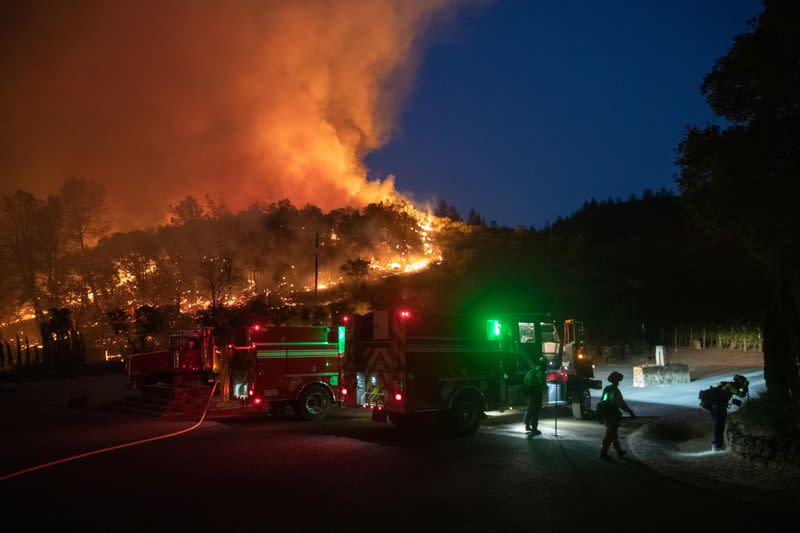 Bomberos protegen una residencia de las llamas del incendio "Glass Fire" en un viñedo en Deer Park, California