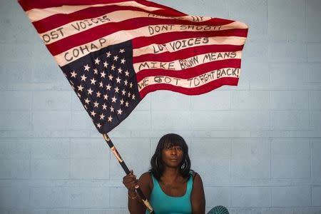 Chocolate, 36, an activist who wants to be identified by only her nickname, waves an American flag upside down while posing for a portrait in Ferguson, Missouri July 24, 2015. REUTERS/Adrees Latif