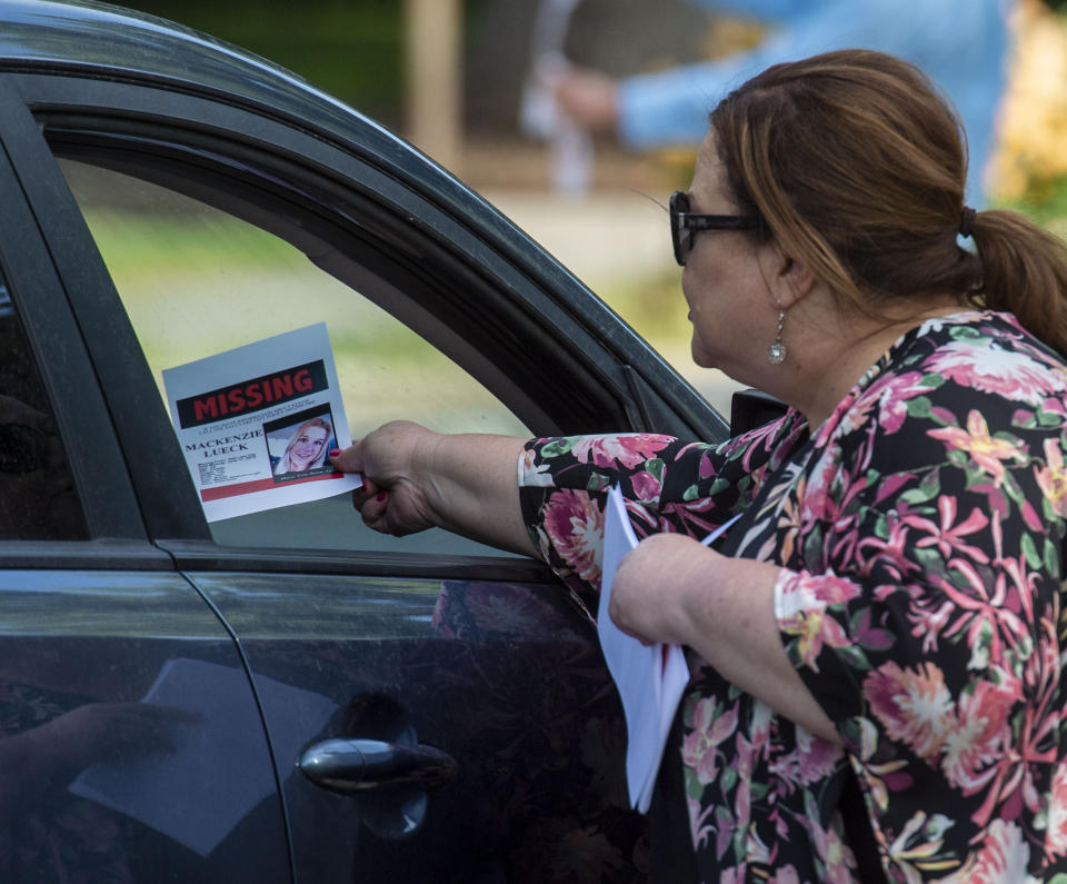 In this Saturday, June 22, 2019 photo, Sara Richardson hands a motorists a sign with Mackenzie Lueck's photo in Liberty Park in Salt Lake City. Police and friends are investigating the disappearance of the 23-year-old University of Utah student, whose last communication with her family said she arrived at Salt Lake City International Airport on Monday, June 17. (Rick Egan/The Salt Lake Tribune via AP)