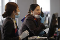 A gate agent pulls down her mask to speak on a radio at Seattle-Tacoma International Airport Tuesday, March 3, 2020, in SeaTac, Wash. Six of the 18 Western Washington residents with the coronavirus have died as health officials rush to test more suspected cases and communities brace for spread of the disease. All confirmed cases of the virus in Washington are in Snohomish and King counties. (AP Photo/Elaine Thompson)