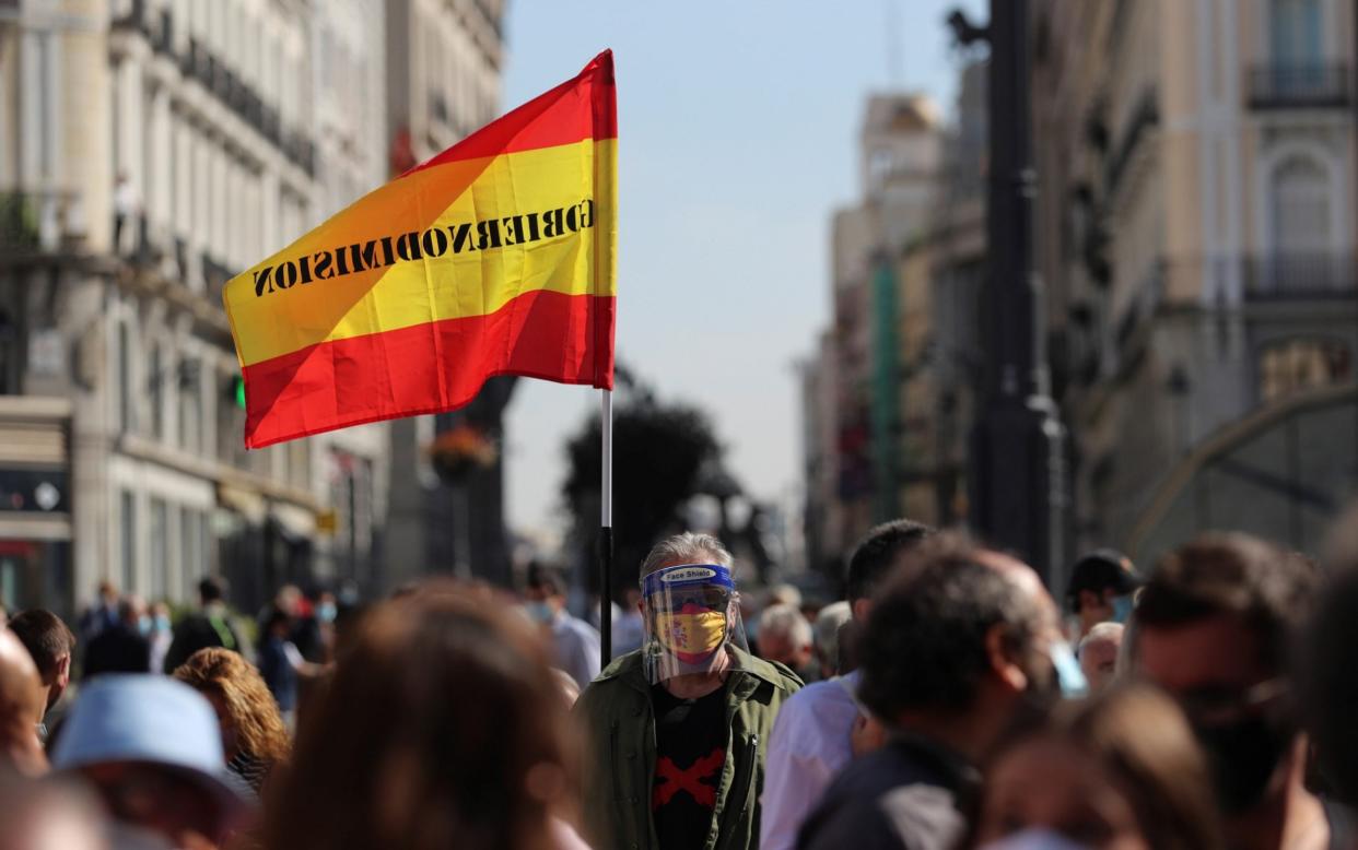 A protester wears a face mask depicting the Spanish national flag during a demonstration against mobility restrictions in 37 areas of Madrid - Rodrigo Jimenez/Shutterstock