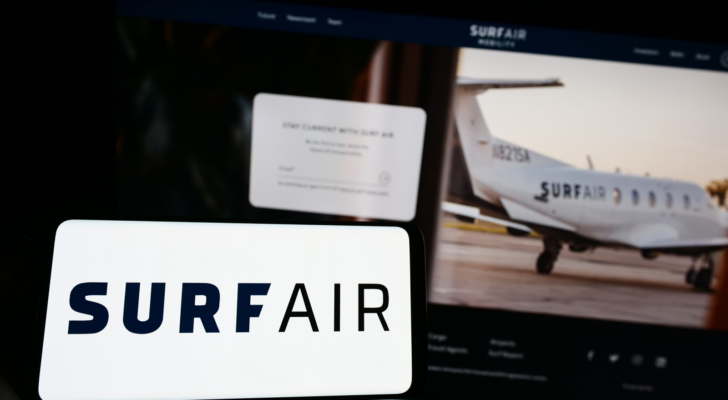 Person holding mobile phone with logo of American aviation company Surf Air Mobility on screen in front of web page. Focus on phone display. Unmodified photo. SRFM stock IPO