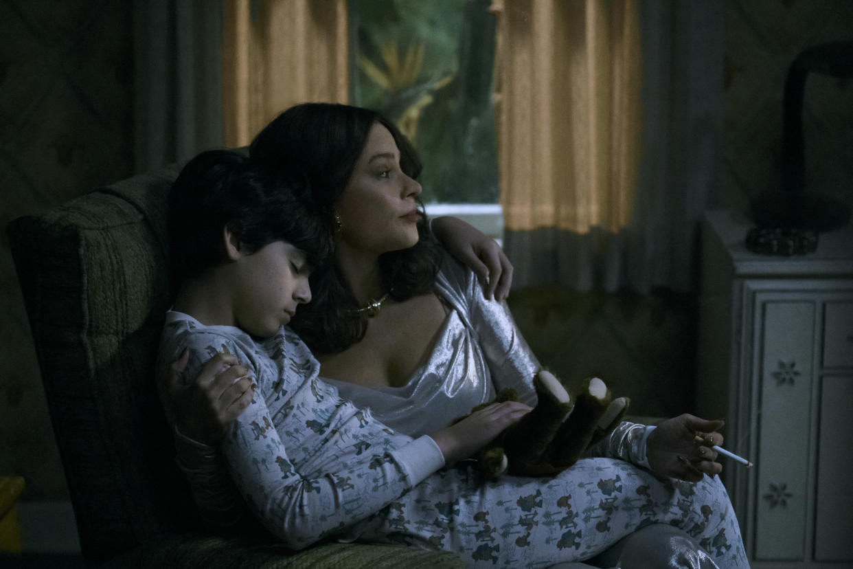 Sofía Vergara playing the role of Griselda Blanco, smoking a cigarette with a sleeping child on her lap.