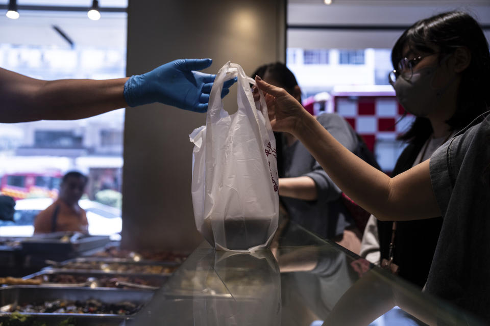 A customer collects a takeaway food plastic bag at Kuen Fat Kitchen in Hong Kong, Wednesday, April 10, 2024. Hong Kong has long been a major producer and consumer of great food, and a great amount of plastic and Styrofoam to go with it. That’s going to change as new legislation aiming to stop the sale and distribution of Styrofoam products and single-use plastic cutlery went into effect on Monday, April 22, 2024. (AP Photo/Louise Delmotte)