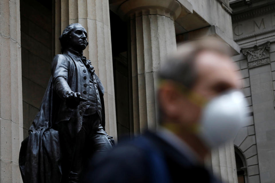 A man walks by a statue of first U.S. President George Washington on the steps of Federal Hall while wearing a surgical mask as more cases of coronavirus were confirmed in Manhattan, New York City, New York, U.S., March 12, 2020. REUTERS/Andrew Kelly