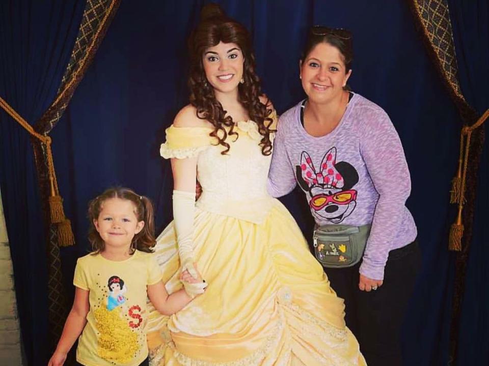 two disney gusts posing for a picture with bell at a character dining spot in epcot at disney world