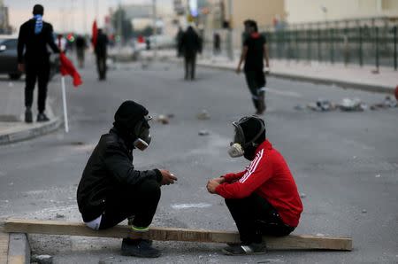 Protesters wearing gas masks rest on a wooden log during clashes after a protest against the execution of prominent Shi'ite Muslim cleric Nimr al-Nimr by Saudi authorities in village of Sitra south of Manama, Bahrain, January 5, 2016. REUTERS/Hamad I Mohammed