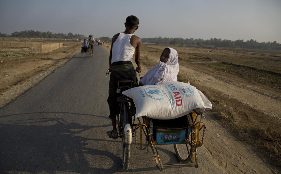 In this Jan. 15, 2014 photo, a Muslim refugee woman travels with a bag of rice that her family received through World Food Program close to Bawda Pa refugee camp in Rakhine state, Myanmar. Severe shortages of food, water and medical care for Rohingya Muslims in western Myanmar are part of a long history of persecution against the religious minority that could amount to "crimes against humanity," according to a statement released Monday April 7, 2014, from Tomas Ojea Quintana, the U.N. Special Rapporteur on the human rights situation in the country. (AP Photo/Gemunu Amarasinghe)