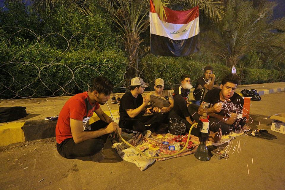 Anti-government protesters rest and smoke a waterpipe during a sit-in near the closed Najaf provincial council, Iraq early Monday, Oct. 28, 2019. Protests have resumed in Iraq after a wave of anti-government protests earlier this month were violently put down. (AP Photo/Anmar Khalil)