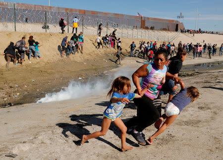 FILE PHOTO: Maria Meza (C), a 40-year-old migrant woman from Honduras, part of a caravan of thousands from Central America trying to reach the United States, runs away from tear gas with her five-year-old twin daughters Saira Mejia Meza (L) and Cheili Mejia Meza (R) in front of the border wall between the U.S and Mexico, in Tijuana, Mexico November 25, 2018. Picture taken November 25, 2018. REUTERS/Kim Kyung-Hoon/File Photo