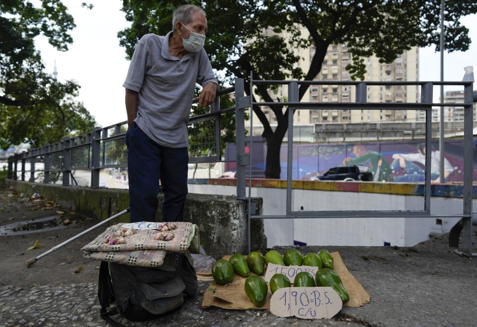 Rafael Rojas sell avocados and garlic on a street in Caracas, Venezuela, Friday, Oct 1, 2021. A new currency with six fewer zeros debuts today in Venezuela, whose currency has been made nearly worthless by years of the world's worst inflation. The new currency tops out at 100 bolivars, a little less than $25 until inflation starts to eat away at that as well. (AP Photo/Ariana Cubillos)