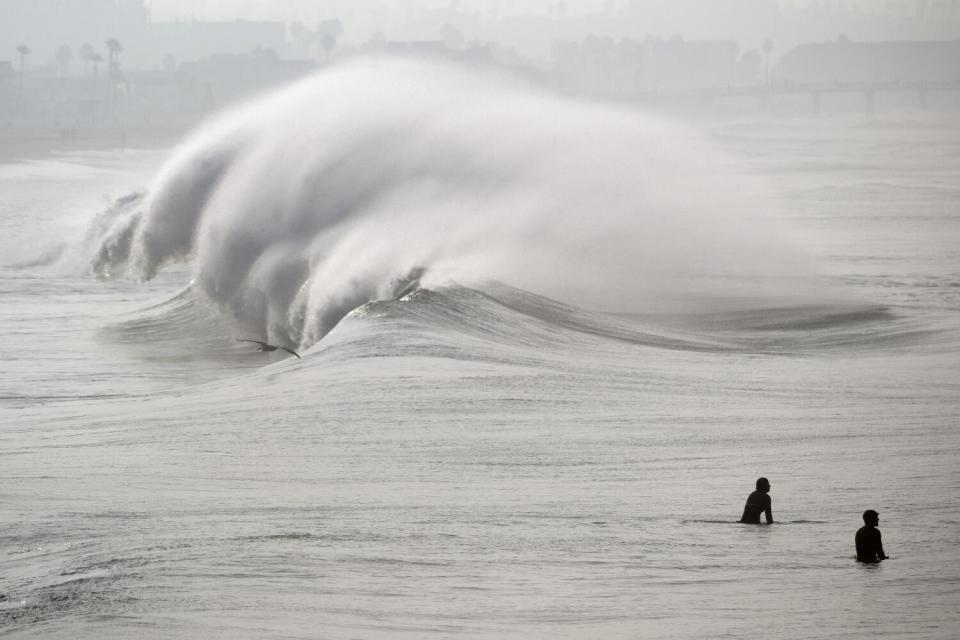 Surfers wait for a wave in high surf at Manhattan Beach, Calif. on Thursday, Dec. 28, 2023.