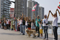 FILE - In this Sunday, Oct. 27, 2019 file photo, anti-government protesters form a human chain as a symbol of unity, during ongoing protests against the Lebanese government, on the Mediterranean waterfront promenade, in Beirut, Lebanon. Protestors’ demands pit them against leaders they accuse of stoking fear to secure sectarian allegiance and of trading economic favors for loyalty. They also put them up against regional allies of local factions. The power-sharing system has largely contained sectarian animosities since the war ended but has also meant that jobs are often allotted according to sectarian quotas instead of merit. AP Photo/Bilal Hussein, File)