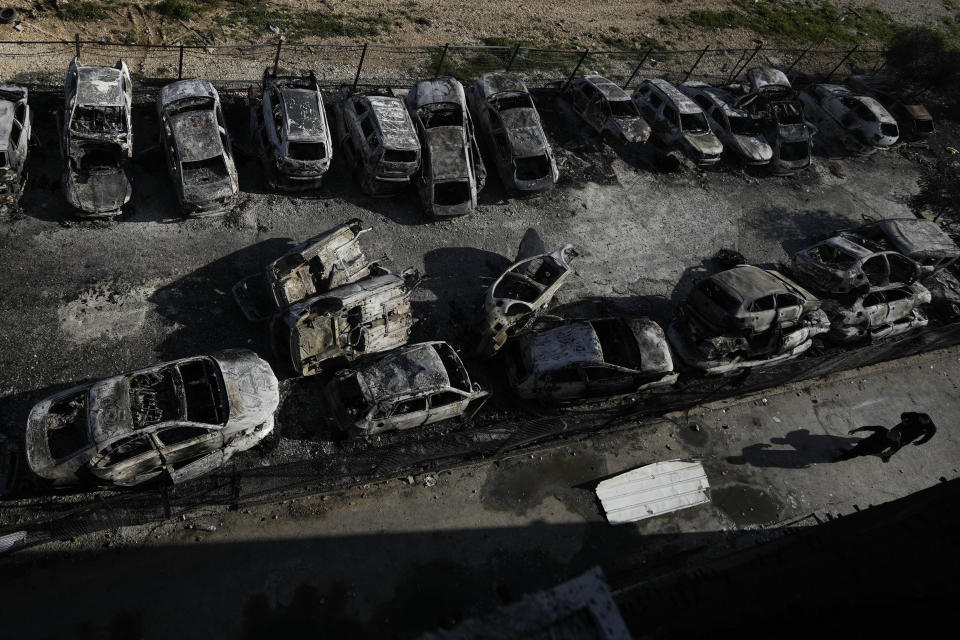 Palestinians walk past burned cars in the town of Hawara, near the West Bank city of Nablus, Monday, Feb. 27, 2023. Scores of Israeli settlers went on a violent rampage in the northern West Bank, setting cars and homes on fire after two settlers were killed by a Palestinian gunman. Palestinian officials say one man was killed and four others were badly wounded. (AP Photo/Majdi Mohammed)